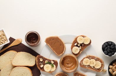 Photo of Toasts with different nut butters, banana slices, blueberries and nuts on white table, flat lay. Space for text