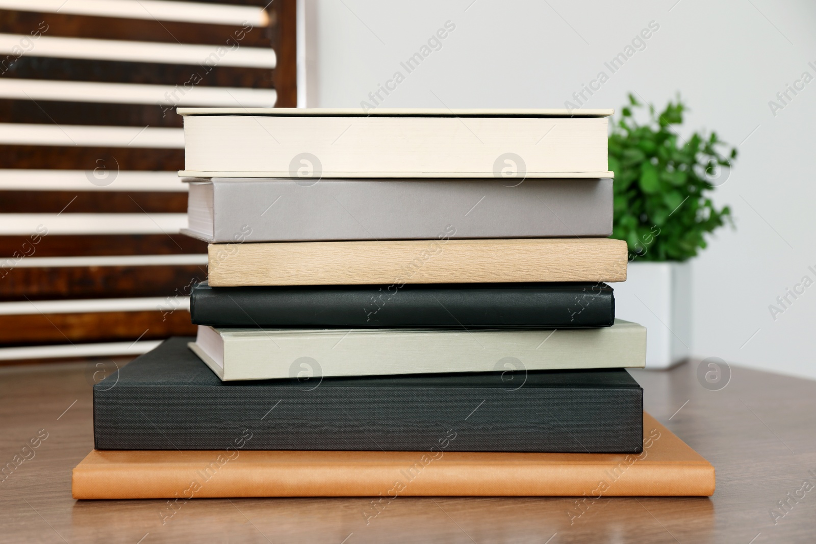 Photo of Stack of different hardcover books on wooden table indoors