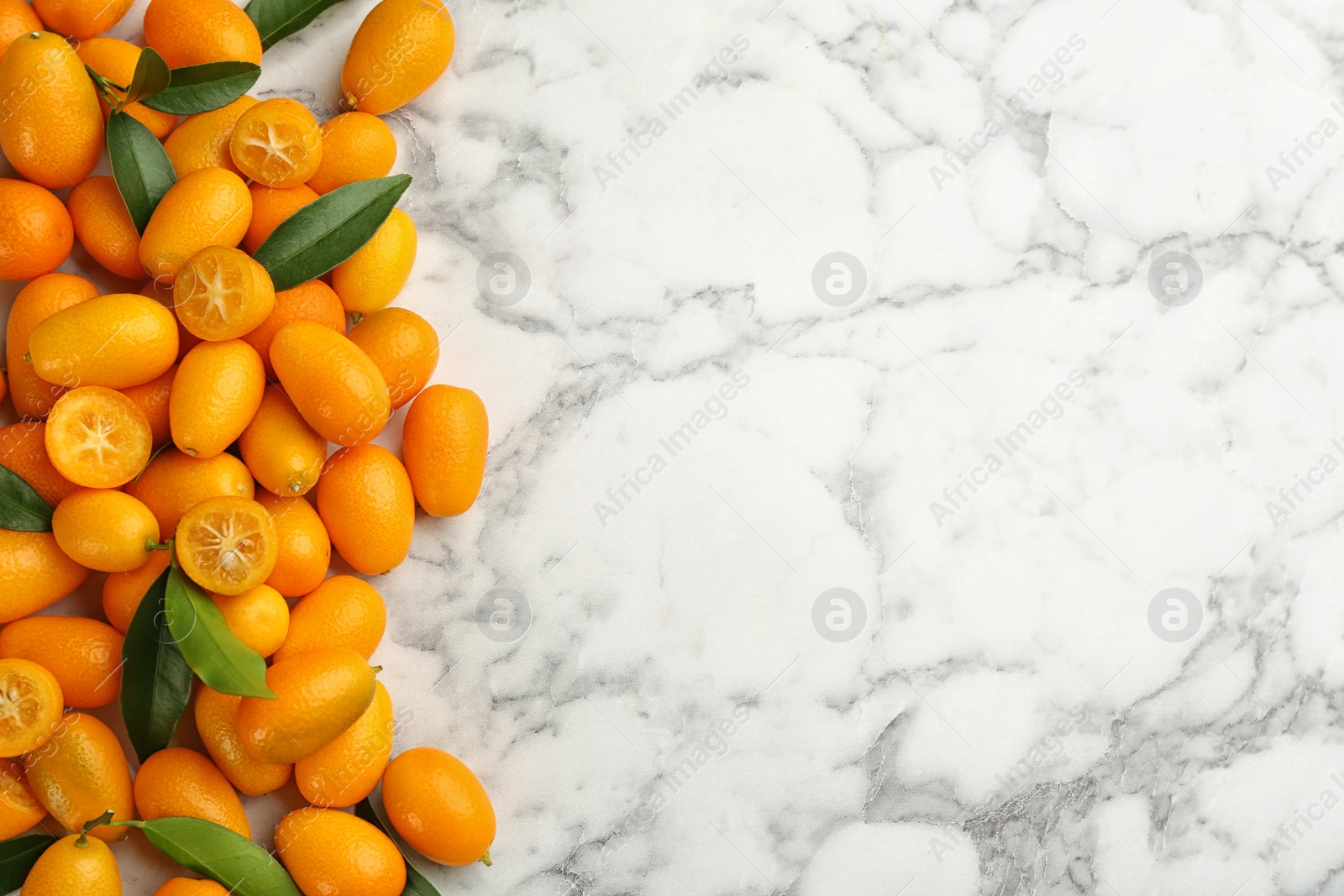 Photo of Fresh ripe kumquats on white marble table, flat lay. Space for text