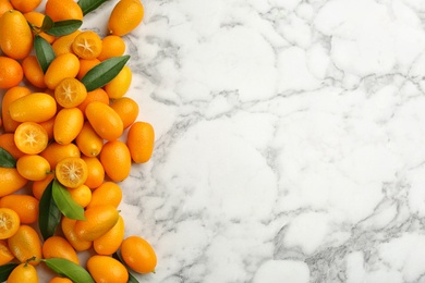 Fresh ripe kumquats on white marble table, flat lay. Space for text