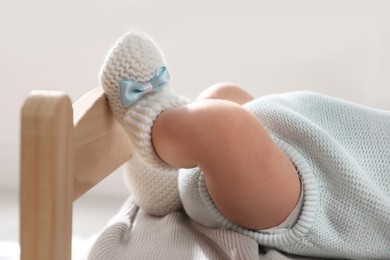 Adorable newborn baby on small wooden bed indoors, closeup