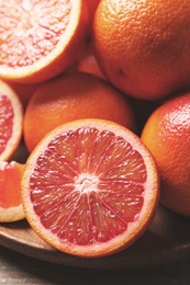 Whole and cut red oranges on wooden table, closeup