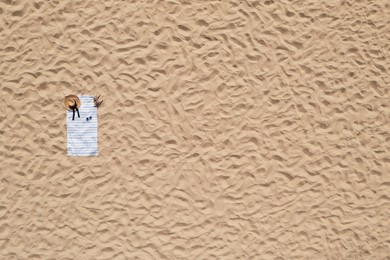 Image of Towel with beach accessories on sand, top view. Space for text