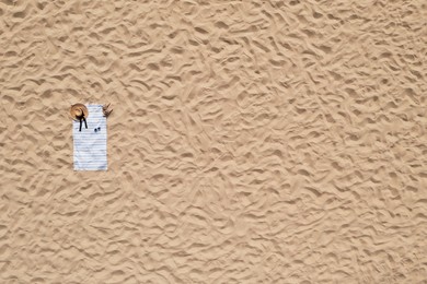 Towel with beach accessories on sand, top view. Space for text