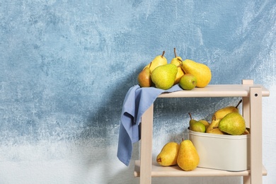 Fresh ripe pears on shelving unit against color background. Space for text