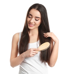 Beautiful young woman with hair brush on white background