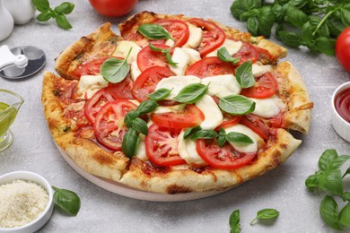 Photo of Delicious Caprese pizza with tomatoes, mozzarella and basil on light grey table