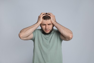 Man suffering from headache on light grey background
