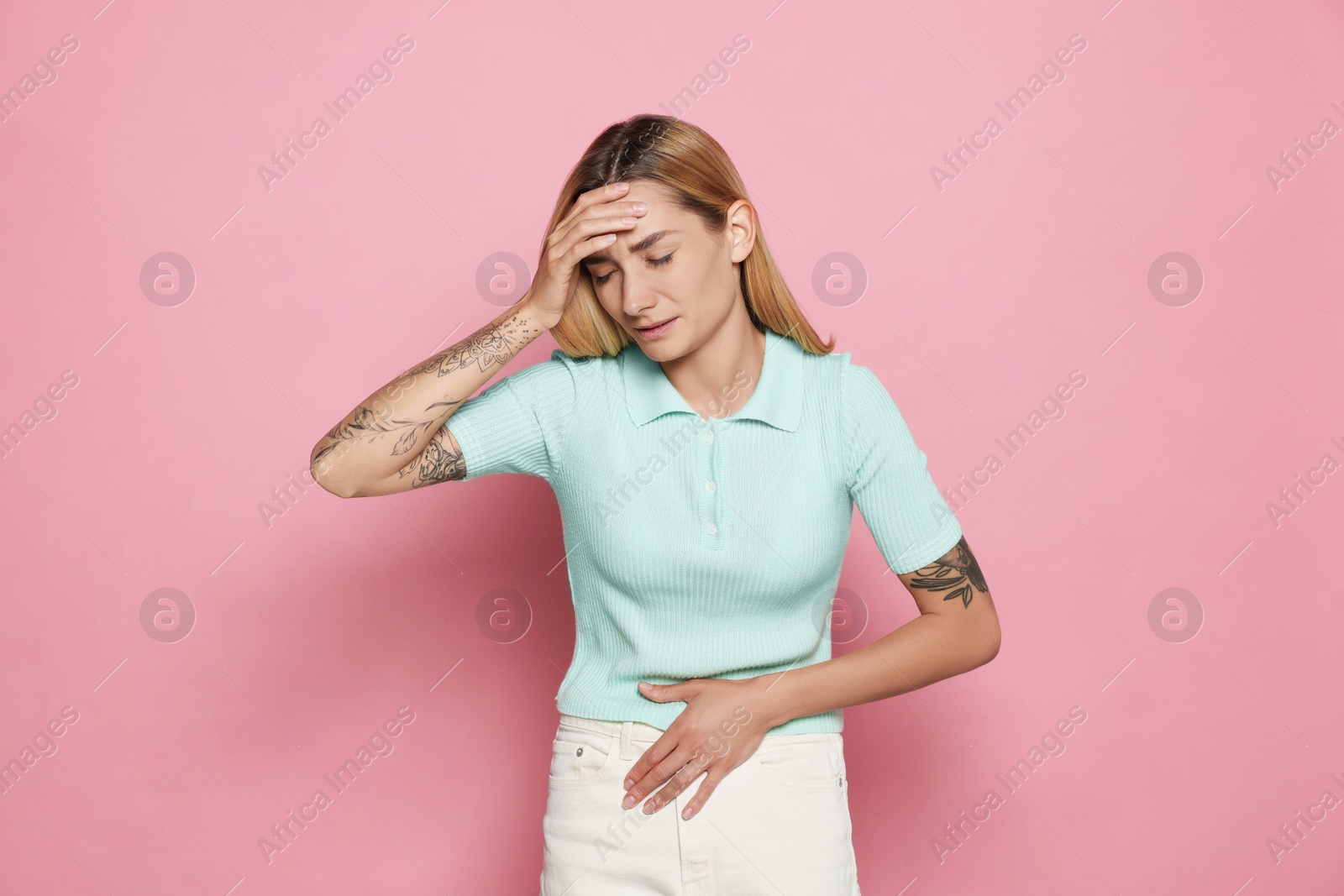 Photo of Young woman suffering from menstrual pain on pink background