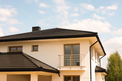 Photo of Beautiful house with black roof against cloudy sky