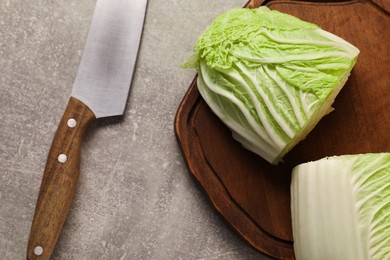 Photo of Halves of fresh Chinese cabbage and knife on light grey table