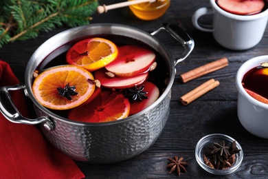Photo of Delicious mulled wine and ingredients on black wooden table