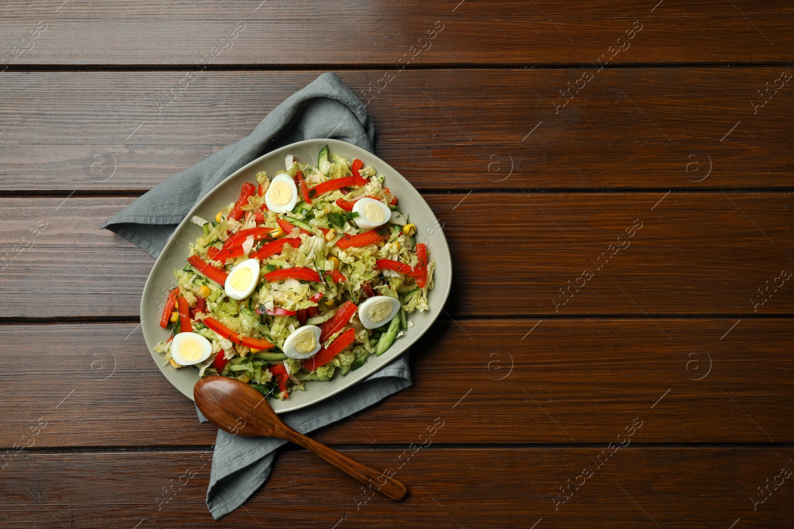 Photo of Delicious salad with Chinese cabbage and quail eggs served on wooden table, top view. Space for text