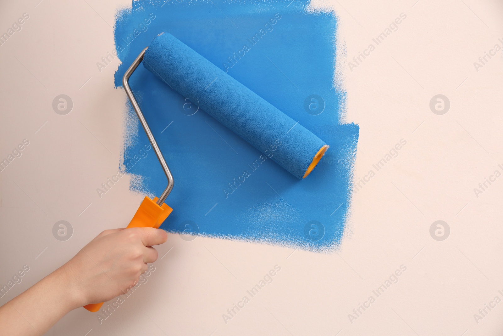 Photo of Woman painting wall with roller, closeup. Redecoration