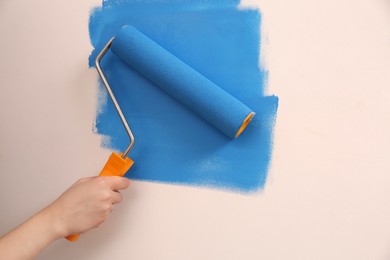 Photo of Woman painting wall with roller, closeup. Redecoration