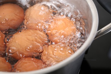 Photo of Chicken eggs boiling in pot on electric stove, closeup