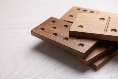 Photo of Wooden domino tiles on white table, closeup