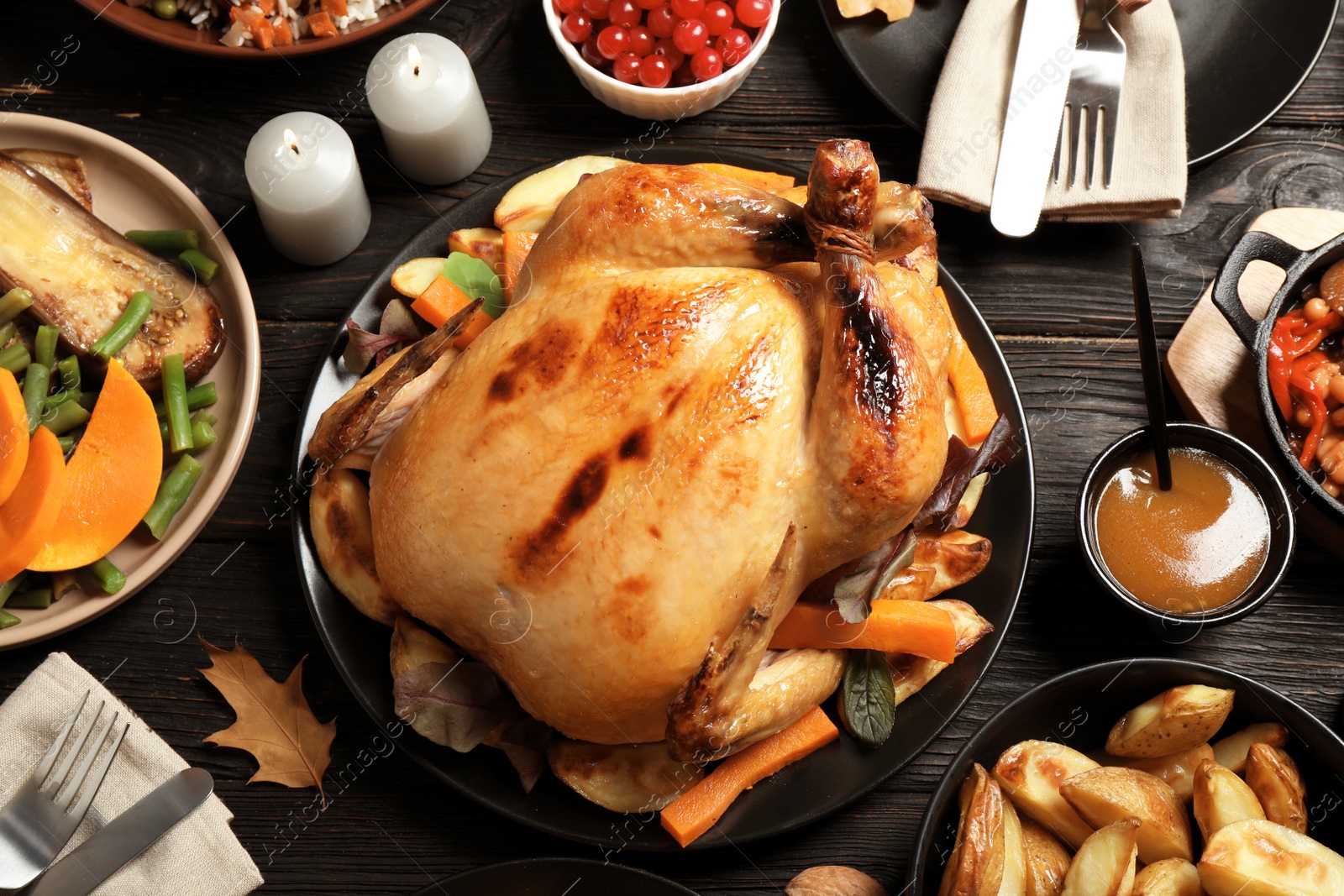 Photo of Traditional Thanksgiving day feast with delicious cooked turkey and other seasonal dishes served on black wooden table, flat lay