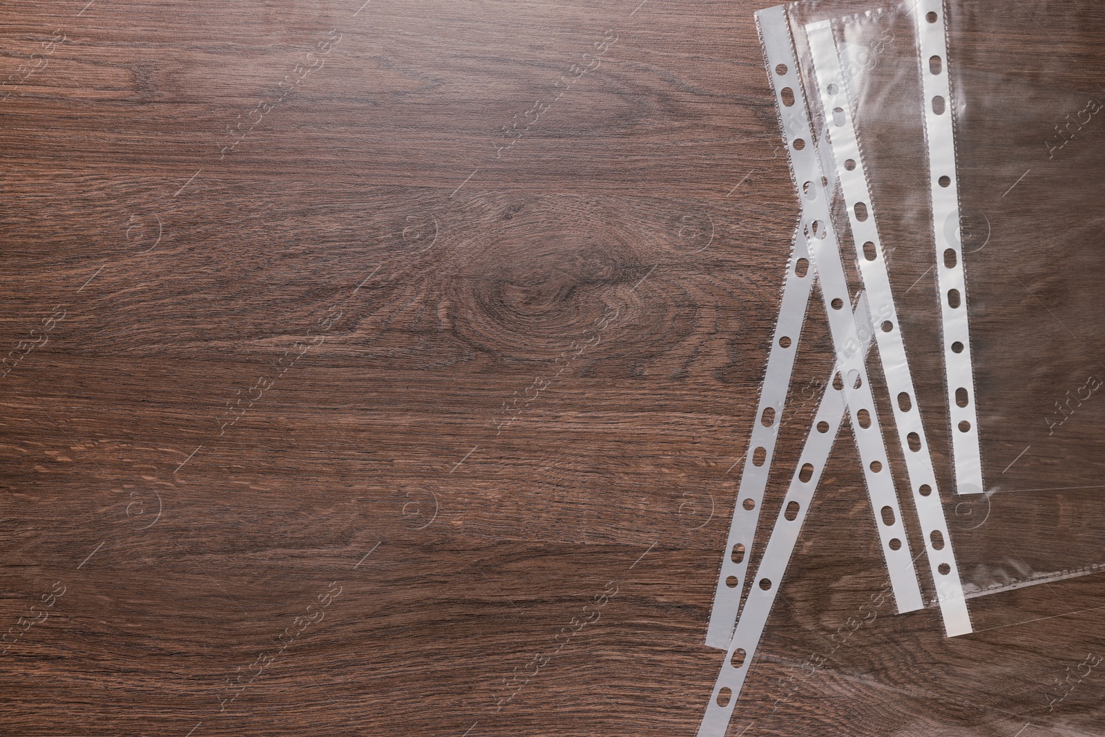 Photo of Punched pockets on wooden table, flat lay. Space for text