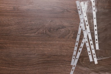 Photo of Punched pockets on wooden table, flat lay. Space for text