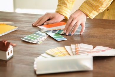 Female designer working with color palette samples at table