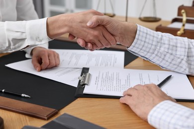 Photo of Lawyer shaking hands with client in office, closeup