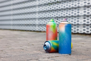 Photo of Used cans of spray paints on pavement, space for text
