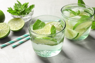 Photo of Refreshing beverage with mint and lime in glasses on table