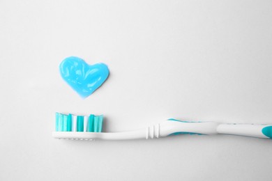 Photo of Heart made with toothpaste and brush on white background, top view