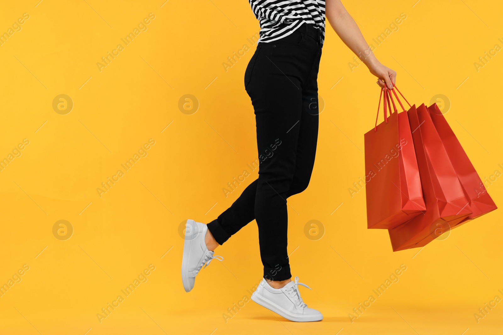 Photo of Woman with shopping bags on yellow background, closeup. Space for text