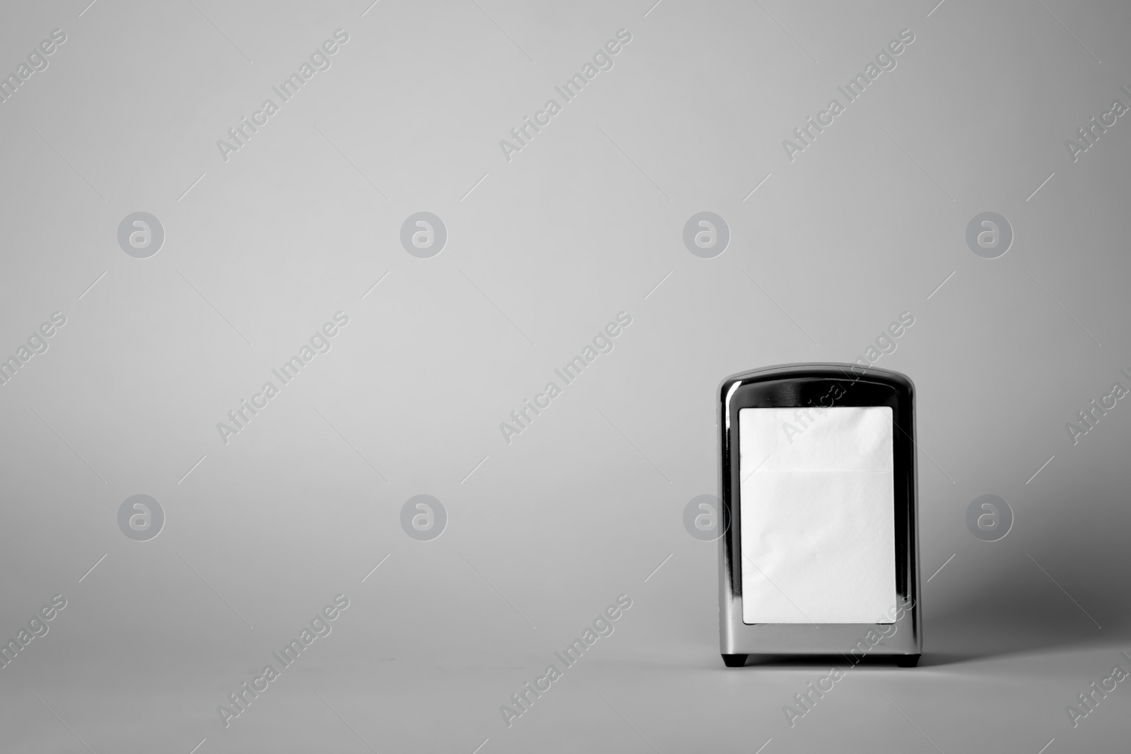 Photo of Napkin holder with paper serviettes on gray background. Space for text