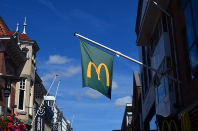 Photo of AMSTERDAM, NETHERLANDS - JULY 16, 2022: McDonald's flag fluttering against blue sky outdoors