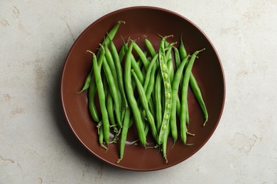 Photo of Fresh green beans in bowl on light grey table, top view