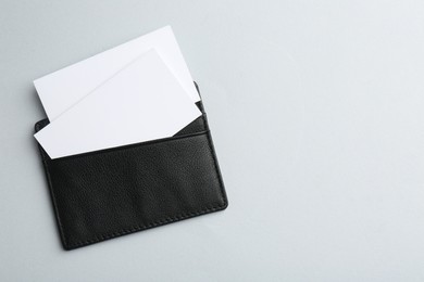 Photo of Leather business card holder with blank cards on light grey background, top view. Space for text