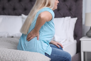 Senior woman suffering from back pain at home, closeup