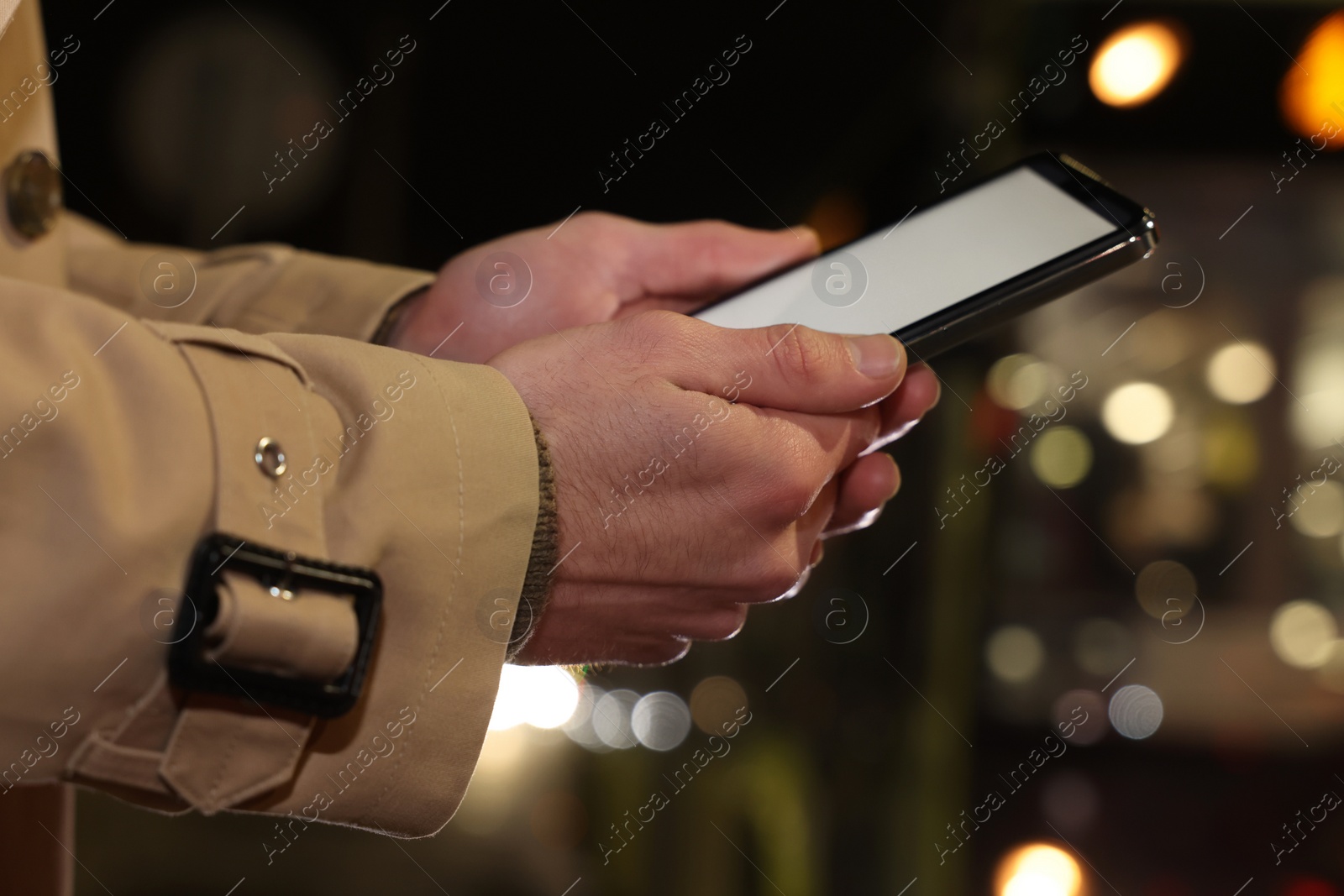 Photo of Man using smartphone on night city street, closeup