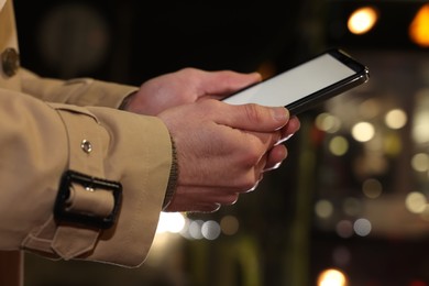 Photo of Man using smartphone on night city street, closeup