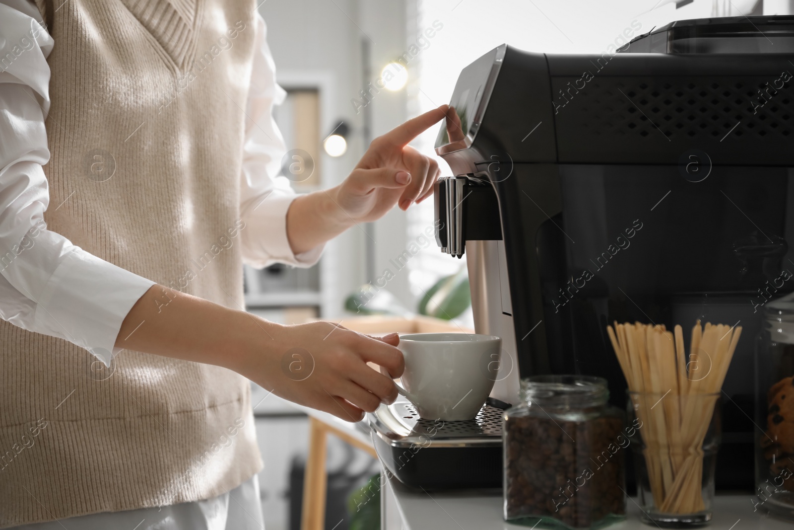 Photo of Young woman preparing fresh aromatic coffee with modern machine in office, closeup