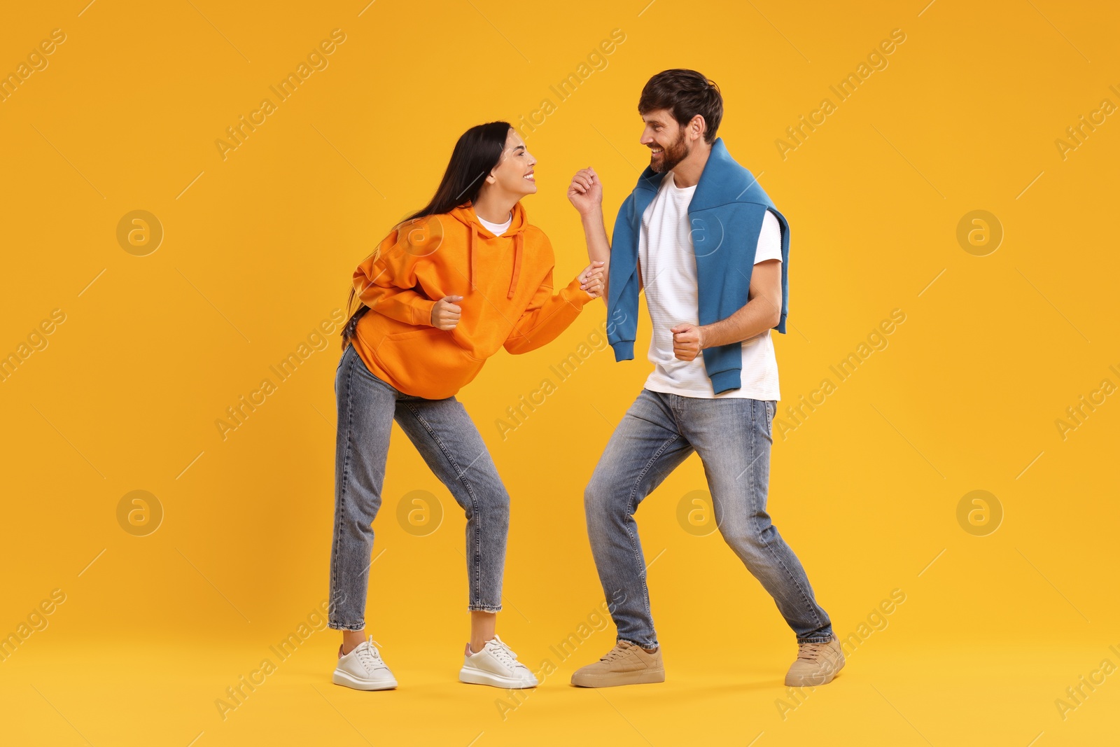 Photo of Happy couple dancing together on orange background