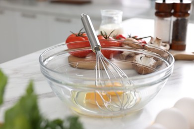 Whisk, bowl, and different ingredients on white marble table indoors