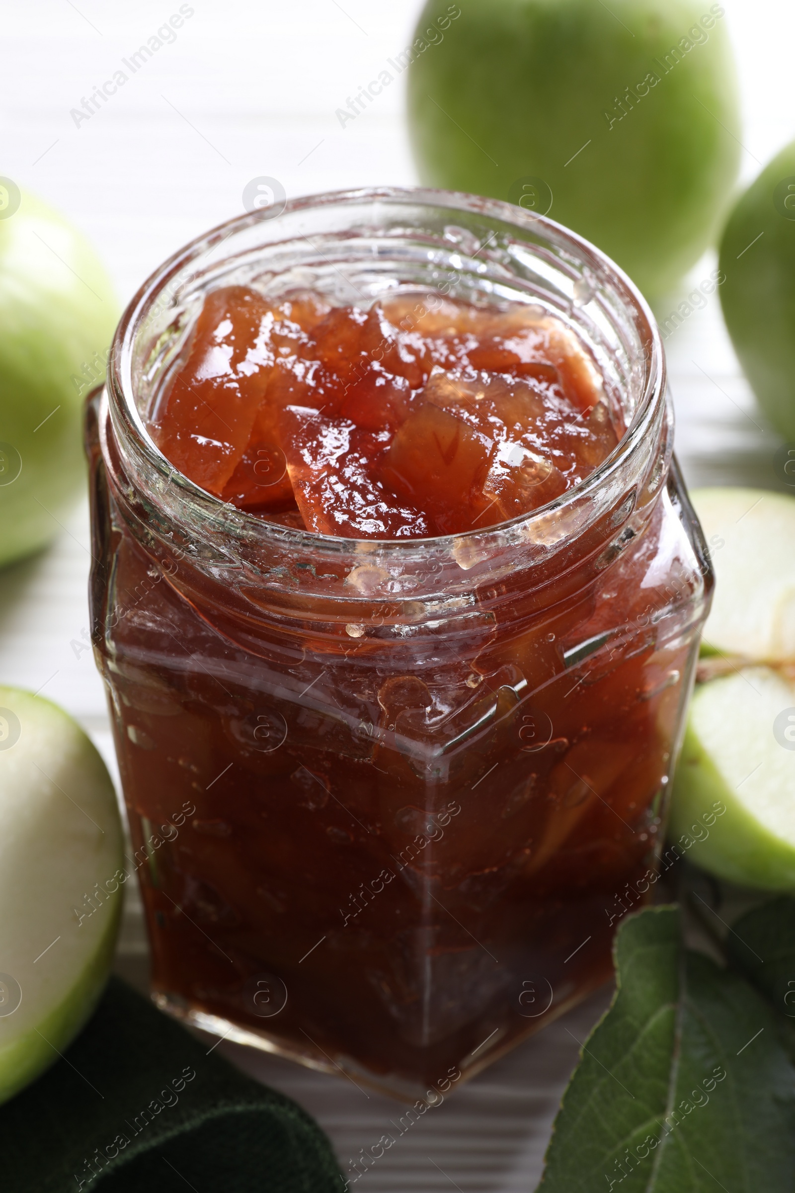 Photo of Glass jar of delicious apple jam on white wooden table, closeup