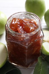 Photo of Glass jar of delicious apple jam on white wooden table, closeup