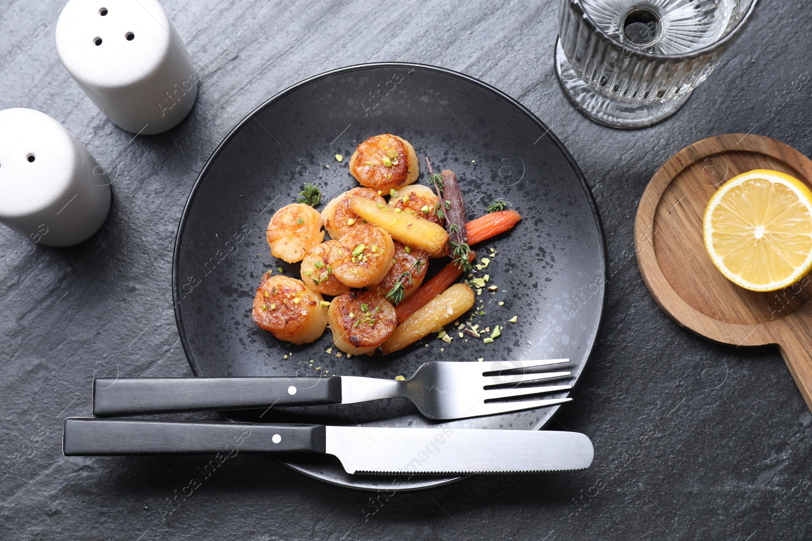 Photo of Delicious fried scallops served on dark gray textured table, flat lay