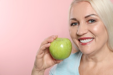 Smiling woman with perfect teeth and green apple on color background. Space for text