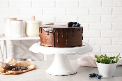 Photo of Fresh delicious homemade chocolate cake with berries on table against brick wall