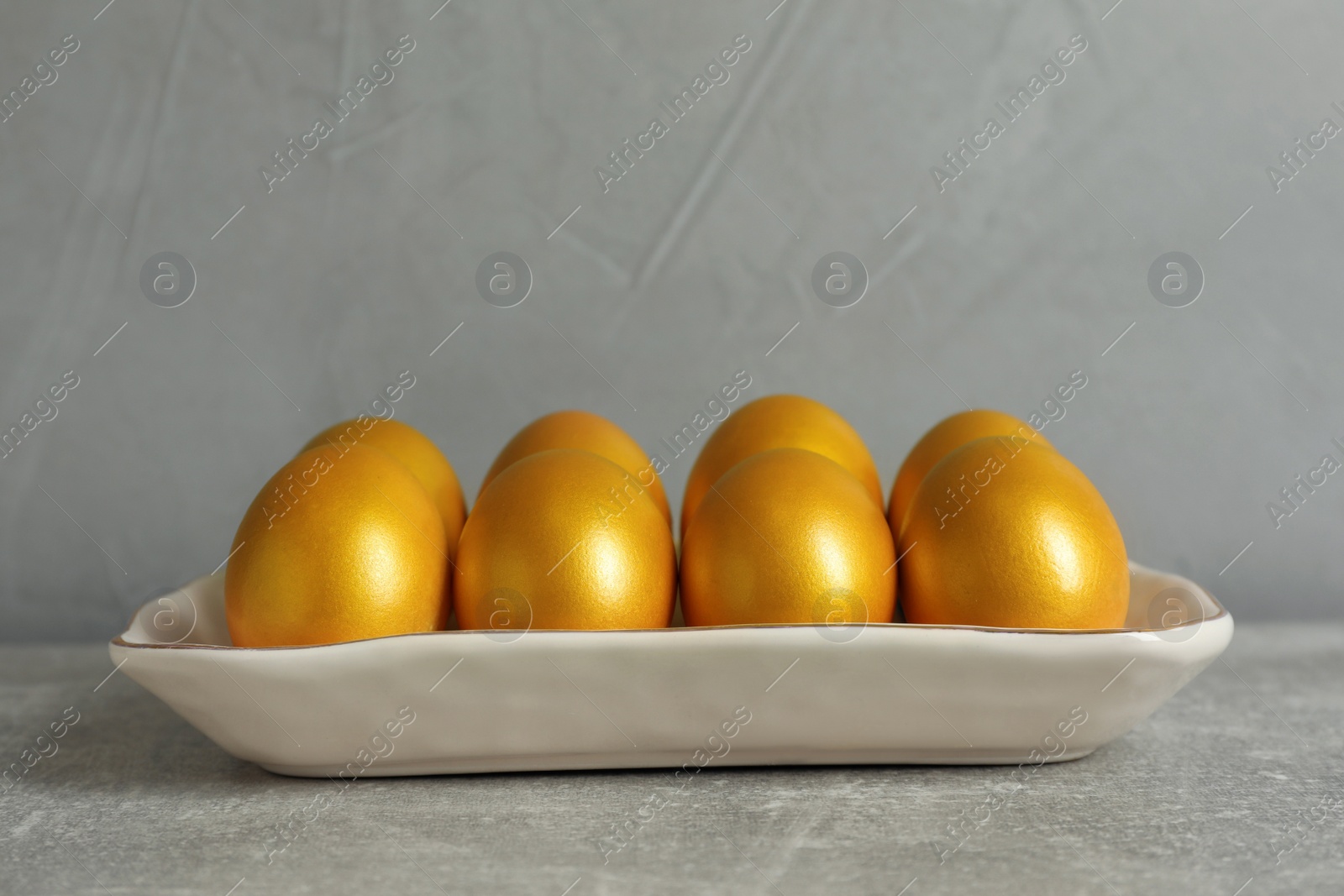 Photo of Shiny golden eggs on light grey table