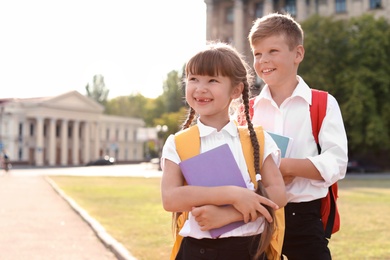 Photo of Little kids with backpacks and notebooks outdoors. Stationery for school