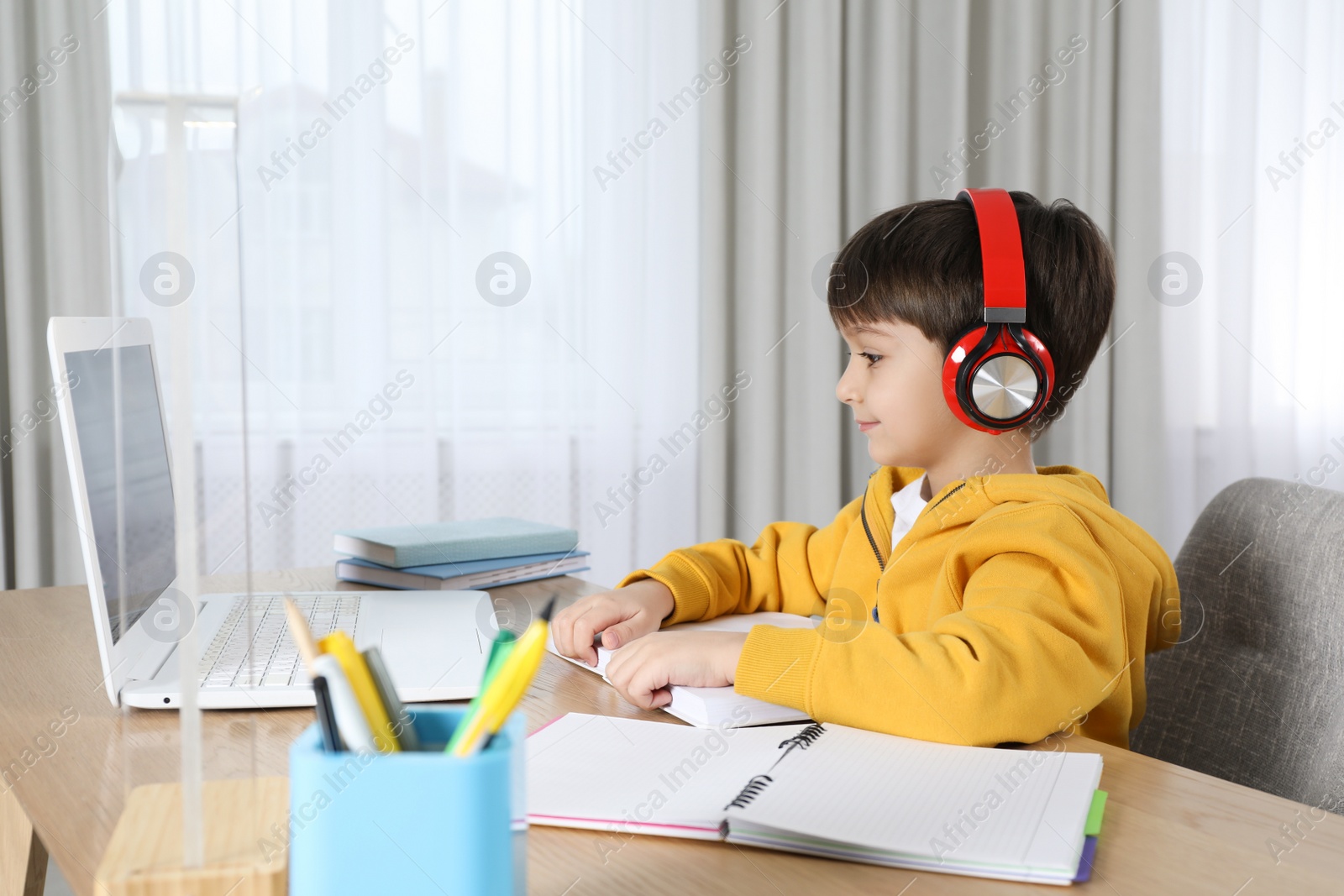 Photo of Cute little boy with modern laptop studying online at home. E-learning