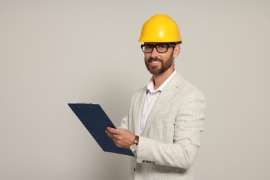 Photo of Professional engineer in hard hat with clipboard on white background