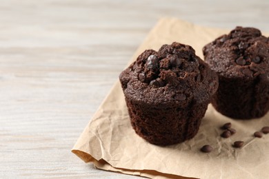 Photo of Delicious chocolate muffins on light wooden table, closeup. Space for text